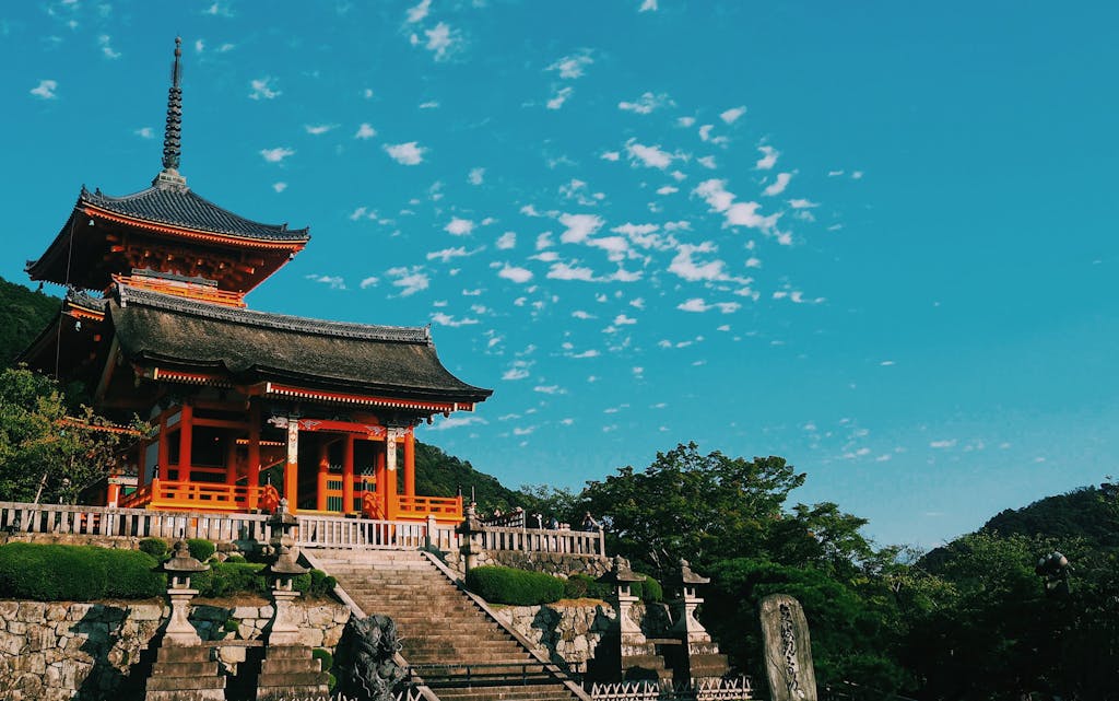 Beautiful view of Kiyomizu Dera Temple in Kyoto, showcasing traditional Japanese architecture under a vibrant sky.