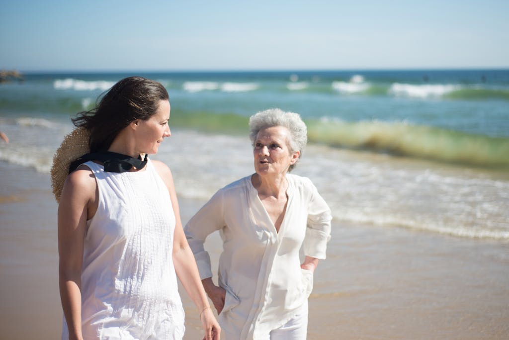 Mother and daughter enjoying a sunny day at the beach in Portugal, walking and talking by the sea.